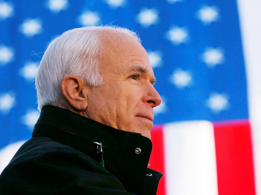 Senator John McCain stands in front of the American flag